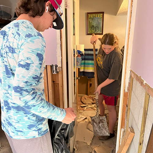 Teenagers clean up moldy drywall removed after home flooded during hurricane in Ft. Myers.