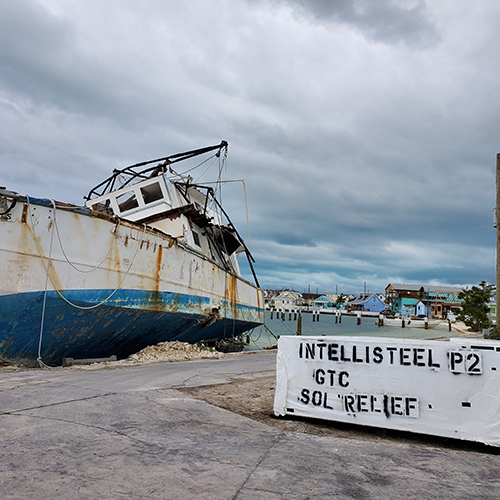 Large fishing boat beached in the Bahamas sitting next to large pallet of building materials.