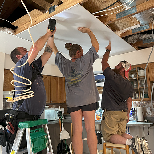 Volunteers replace drywall of the ceiling in a house that was damaged during Hurricane Ian.