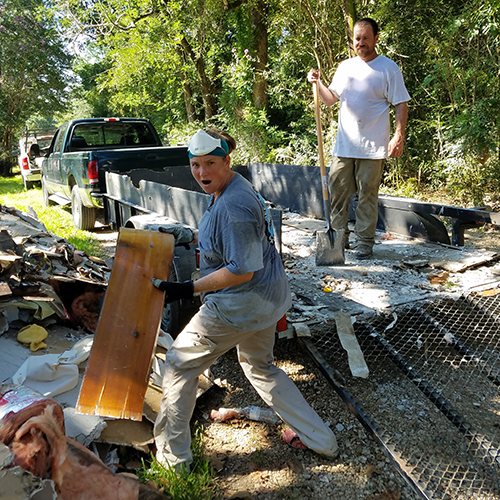 Woman makes funny faces while her husband watches in dismay while doing debris removal.