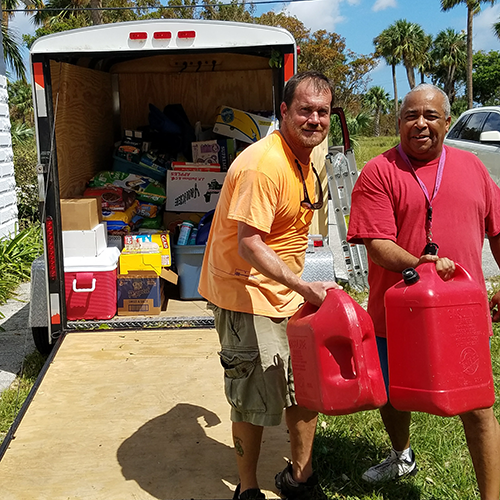 Two men pose in front of a trailer loaded with donations for distribution and relief center.