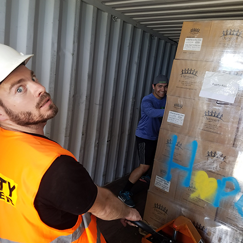 Volunteer man dramatically unloading a pallet of donations of food from container.