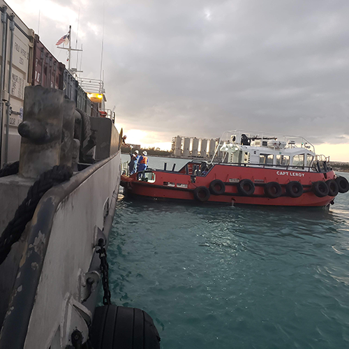 Harbor pilot boat pulled up to shipping boat to receive dinner for the crew cooked by missionaries.