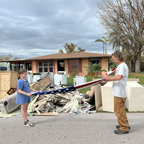 Man and child refold flag that was salvaged after home flooded during a hurricane.