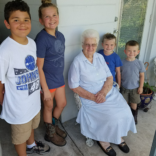 Children smile with homeowner after cleaning up her yard.