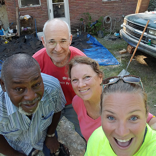 Volunteers and homeowner pose in front of home.