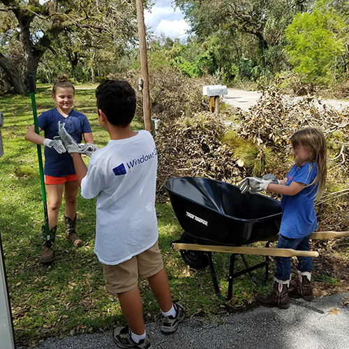 Children help with debris removal from an elderly widow's yard after storm.