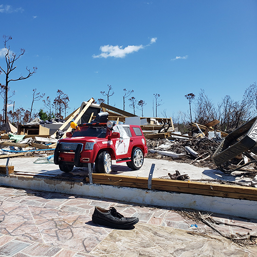 Child's toy car sitting on the foundation of a house destroyed by a hurricane.