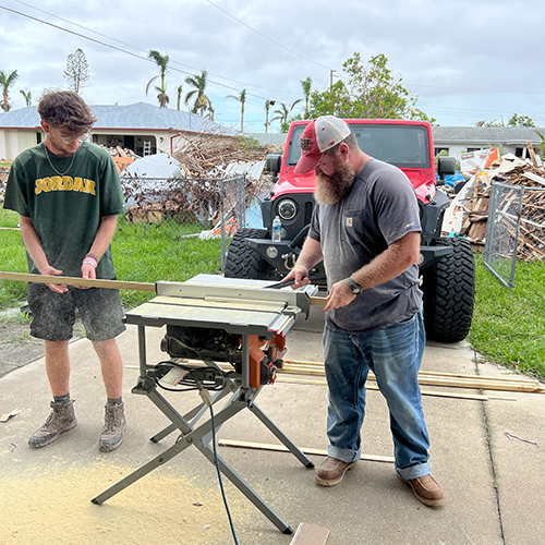 Volunteers cut wood for repairs on a home that flooded during a hurricane.