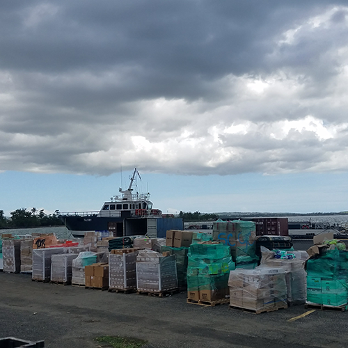 90 pallets of donations and supplies stacked on the dock in front of boat after being transported to Puerto Rico in the aftermath of a hurricane.