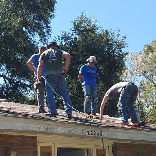 Volunteers get lesson in replacing roofing shingles from local roofer.