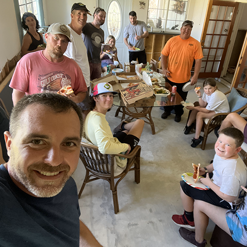 Volunteer team taking a lunch break during mission trip to muck out houses and replace drywall during hurricane response.