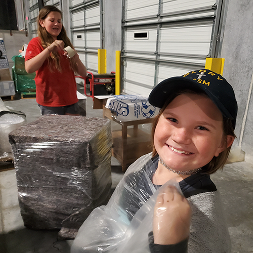 Two girls wrap furniture to be shipped to the Bahamas after Hurricane Dorian destroyed many homes.